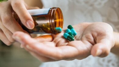 moteris deda vitaminus į delną