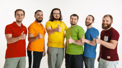 vyrų būrys stovi iškėlę nykščius