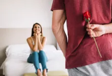vyras laiko gėlę už nugaros