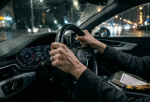 Moters rankos stipriai sugniaužusios vairo odą tamsiame automobilio salone