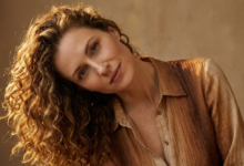 Moteris su tobulo kritimo, žvilgančiomis ir elastingomis natūraliomis garbanomis, lengvai pakreipusi galvą