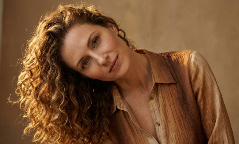 Moteris su tobulo kritimo, žvilgančiomis ir elastingomis natūraliomis garbanomis, lengvai pakreipusi galvą