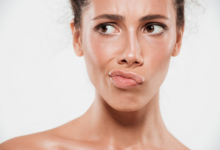 jaunos moters veidas iš artis su perkreiptom lūpom