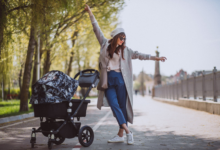 moteris vaikšto su vežimėliu parke
