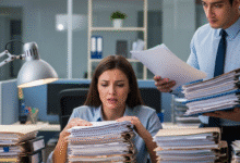 moters sėdi prie sato su šūsnimi dokumentų