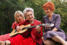 pusamžė moteris groja gitara draugėms