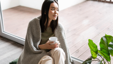 japonė moteris sėdi namie su puodeliu rankoje prie lango