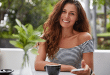 jauna besišypsanti moteris sėdi kavinėje