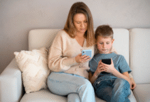 mama ir vaikas sėdi ant sofos ir kiekvienas žiūri į savo telefoną