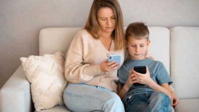 mama ir vaikas sėdi ant sofos ir kiekvienas žiūri į savo telefoną