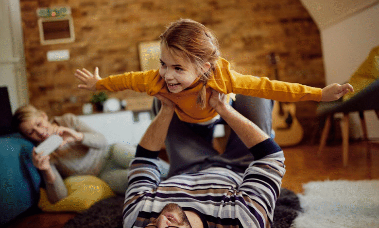tėtis žaidžia su dukra, o mama fotografuoja