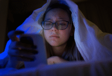 mergaitė lovoje su išmaniuoju telefonu prieš miegą
