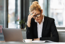 moteris sėdi ofise pasirėmusi ranka galvą