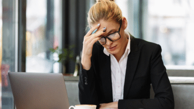 moteris sėdi ofise pasirėmusi ranka galvą