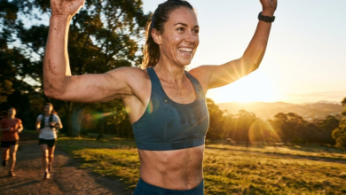 moteris bėga maratoną ir šypsosi iškėlusi rankas
