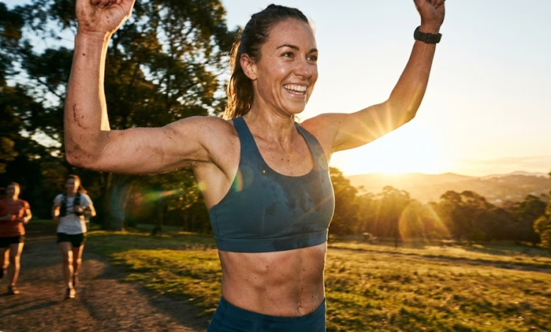 moteris bėga maratoną ir šypsosi iškėlusi rankas