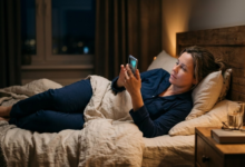 moteris 40 metų vakare guli lovoje ir scrolina telefone